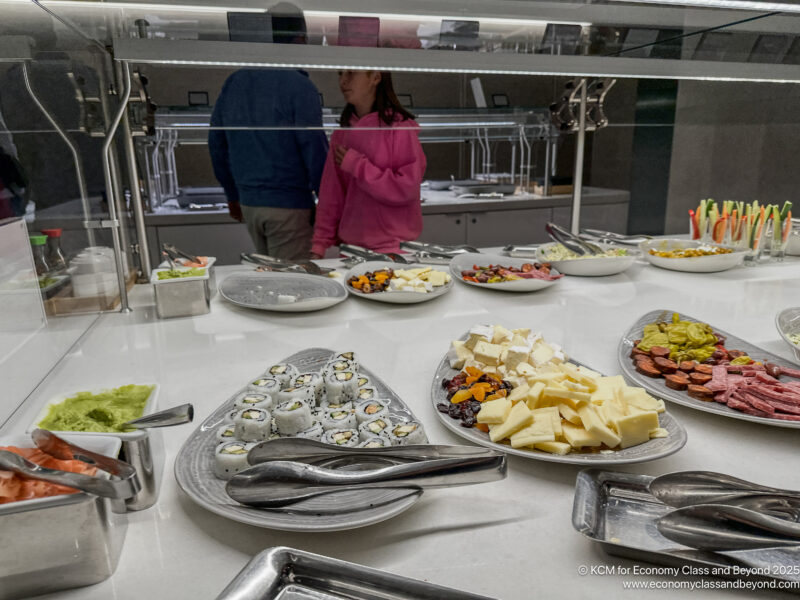 a buffet table with plates of food and a woman standing behind