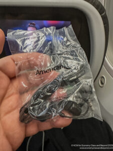 a hand holding a black earbuds in a plastic bag