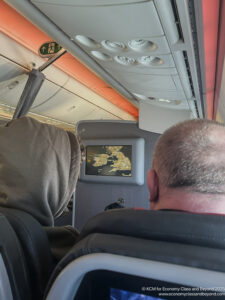 a man looking at a screen on an airplane