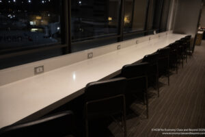 a long white table with chairs in front of a window