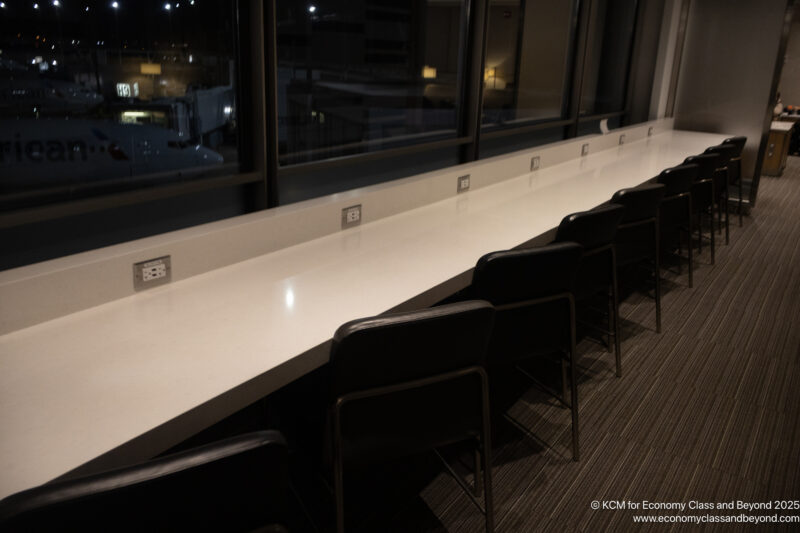 a long white table with chairs in front of a window