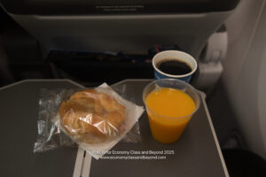 a breakfast on a tray with a drink and a croissant