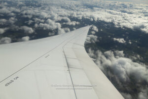 an wing of an airplane above clouds