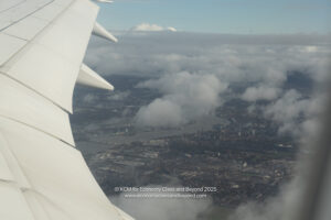 an airplane wing with a city and clouds