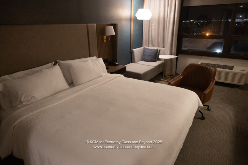 a bed with white sheets and pillows in a hotel room