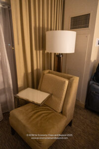 a chair with a table and a lamp in a room