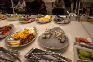 a table with plates of food and people sitting at tables