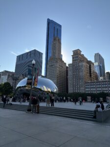 a group of people in a park with a large reflective sculpture