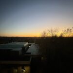 a building with trees and a sunset