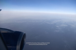 an airplane wing with a blue sky and clouds