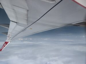 an airplane wing with clouds in the background