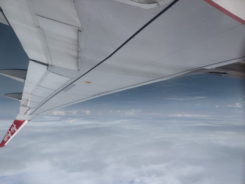 an airplane wing with clouds in the background