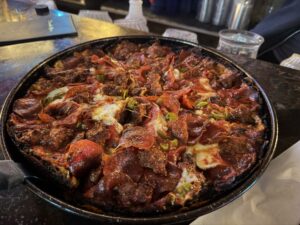 a pizza with pepperoni and jalapenos on a black pan