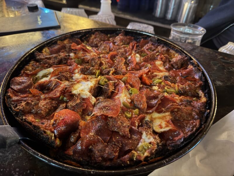 a pizza with pepperoni and jalapenos on a black pan