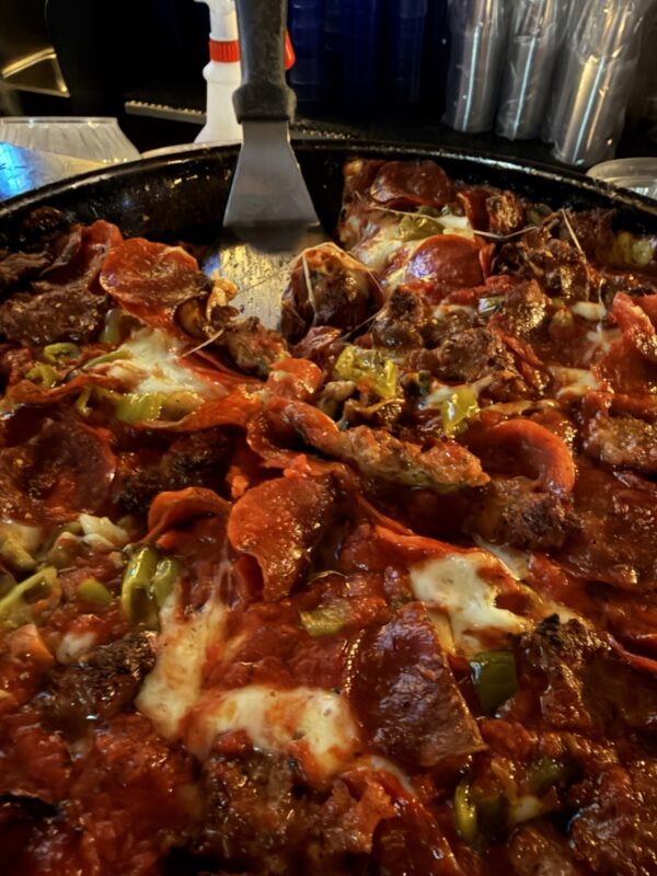 a pizza with meat and vegetables on a pan