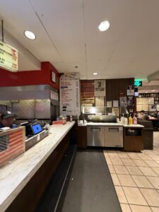 a restaurant with a counter and people sitting in the chairs