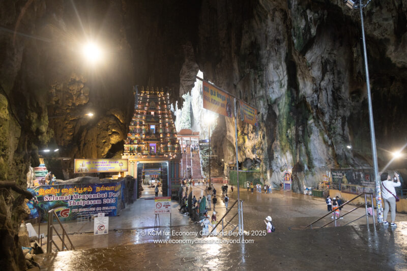 a cave with Batu Caves and people walking in it