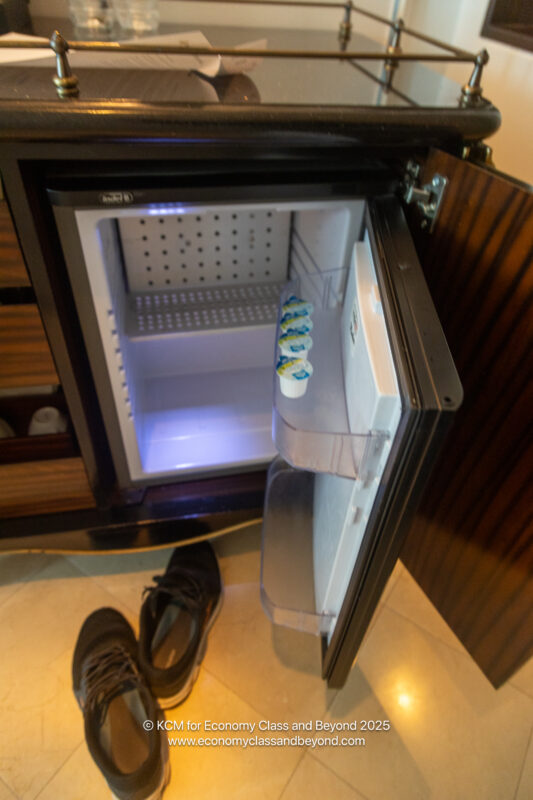 a small refrigerator with a shelf and shoes