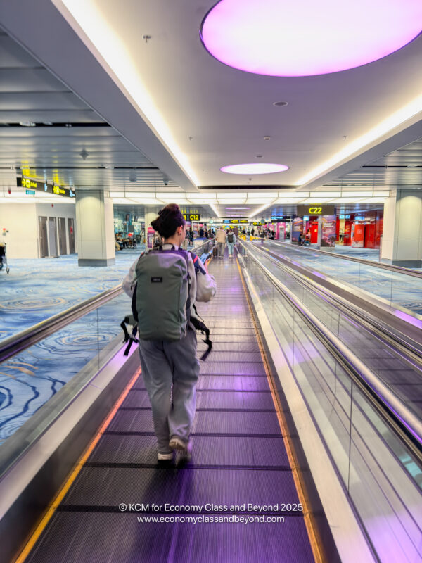 a woman walking on a moving walkway in an airport