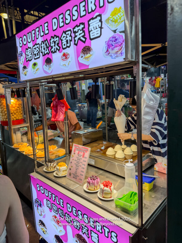 a food stand with a sign and a person holding a bag of ice cream