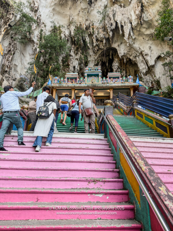 a group of people climbing up stairs in front of a cave