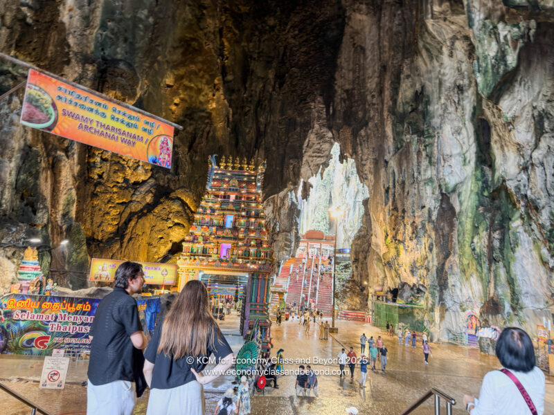 people walking in a cave with Batu Caves in the background