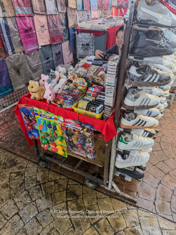 a woman standing behind a cart with a variety of items