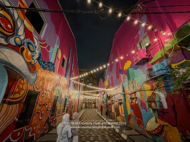 a group of people walking down a narrow alley with colorful buildings
