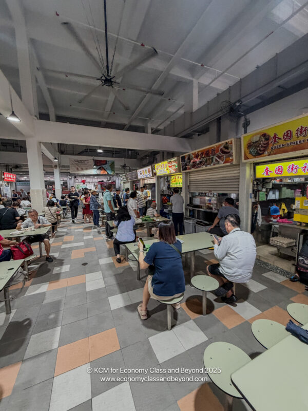 a group of people sitting at tables in a food court