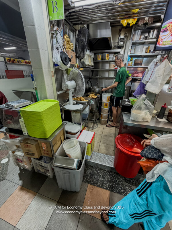 a man standing in a kitchen with a fan and a man standing in a room