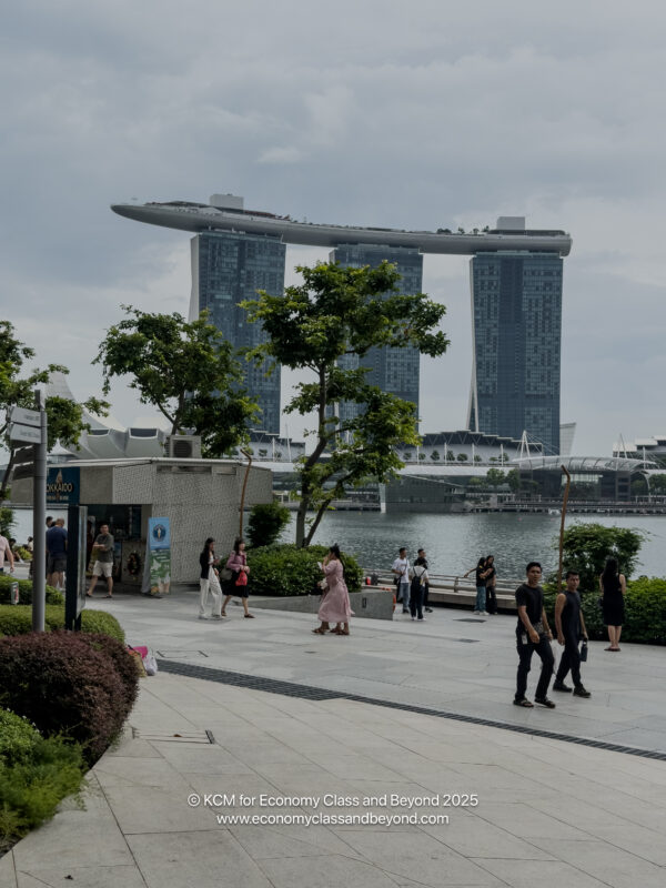 a group of people walking on a sidewalk by a body of water