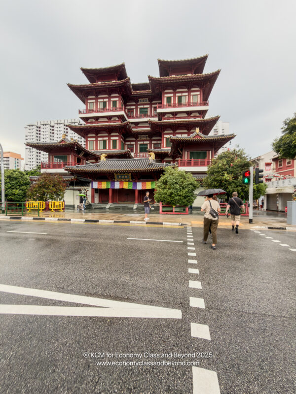 a building with a red roof and a couple people walking on the street