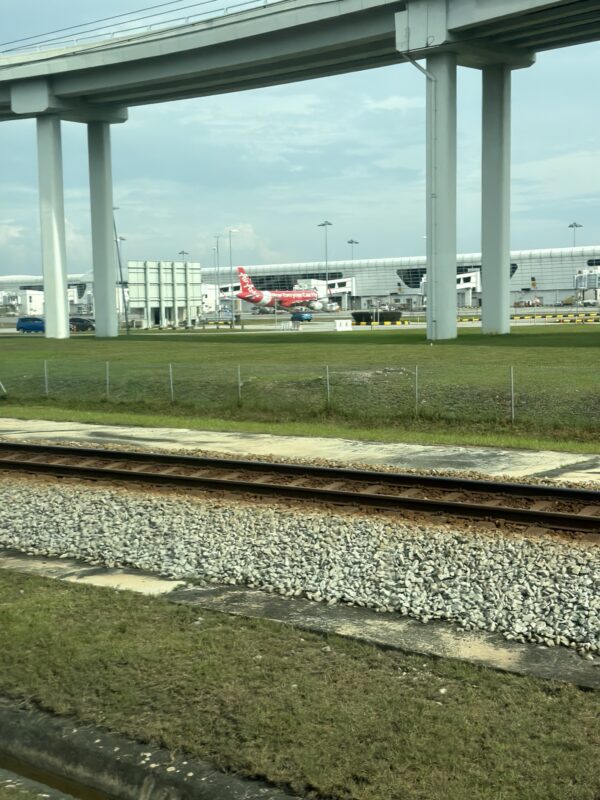 train tracks and a building with a plane in the background