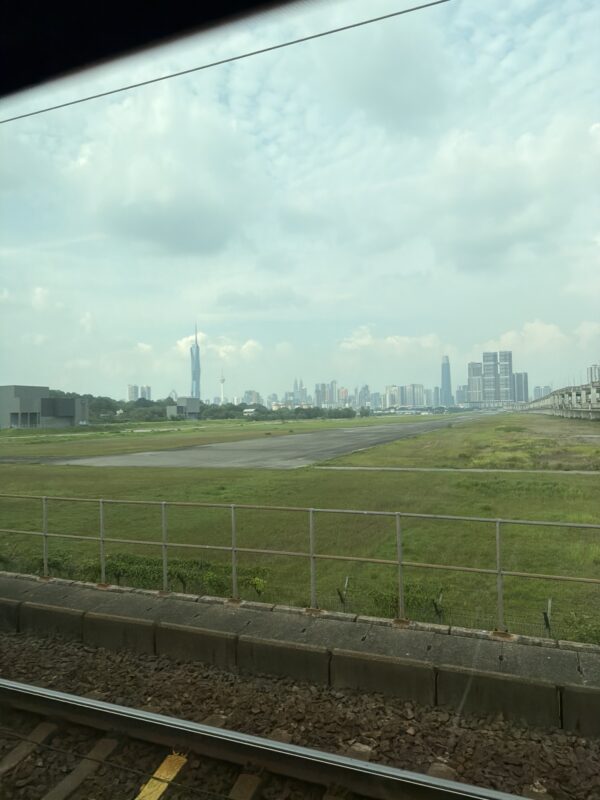a field with grass and buildings in the background