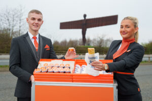 easyJet's Free Sausage Rolls & 'Destination Dips, - Kurt Allen and Elisha Horseman, easyJet cabin crew, serving up free sausage rolls and limited-edition ‘Destination Dips’ at the Angel of the North as the airline and tour operator team up with Greggs to celebrate the launch of its new Newcastle base. Issue date: Monday March 23, 2026. The partnership introduces five sausage roll dipping sauces inspired by new easyJet holidays destinations including Sangria, Affogato, Harissa Ketchup, Tarte Tatin, and Kebab, offered across all international easyJet flights from Newcastle Airport today and across the city. Image, easyJet