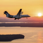 Heart Aerospace’s battery-electric X1 demonstrator banks east toward the rising sun during its first flight near Plattsburgh, New York, in August 2026, with Lake Champlain in the distance.